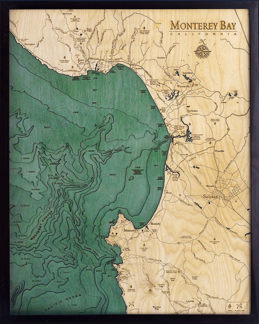 Monterey Bay, California 3D layered wood map in laser-cut Baltic birch, shown framed against a light wall