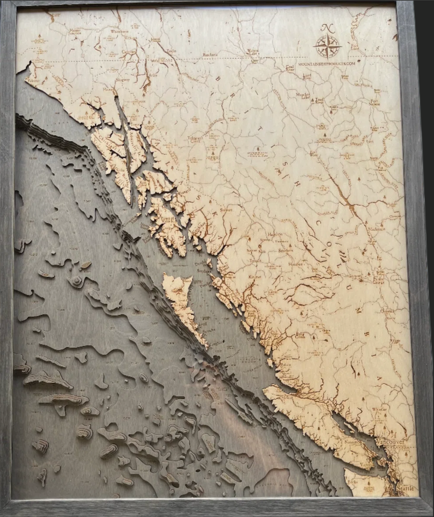 British Columbia Coast 3D layered wood map in laser-cut Baltic birch, shown framed against a light wall