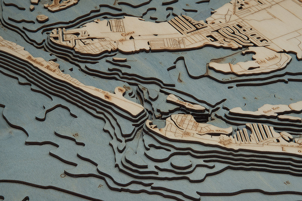 Anna Maria Island, Florida 3D layered wood map in laser-cut Baltic birch, shown framed against a light wall