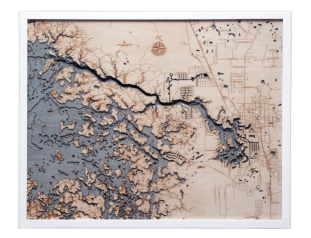 Crystal River, Florida 3D layered wood map in laser-cut Baltic birch, shown framed against a light wall