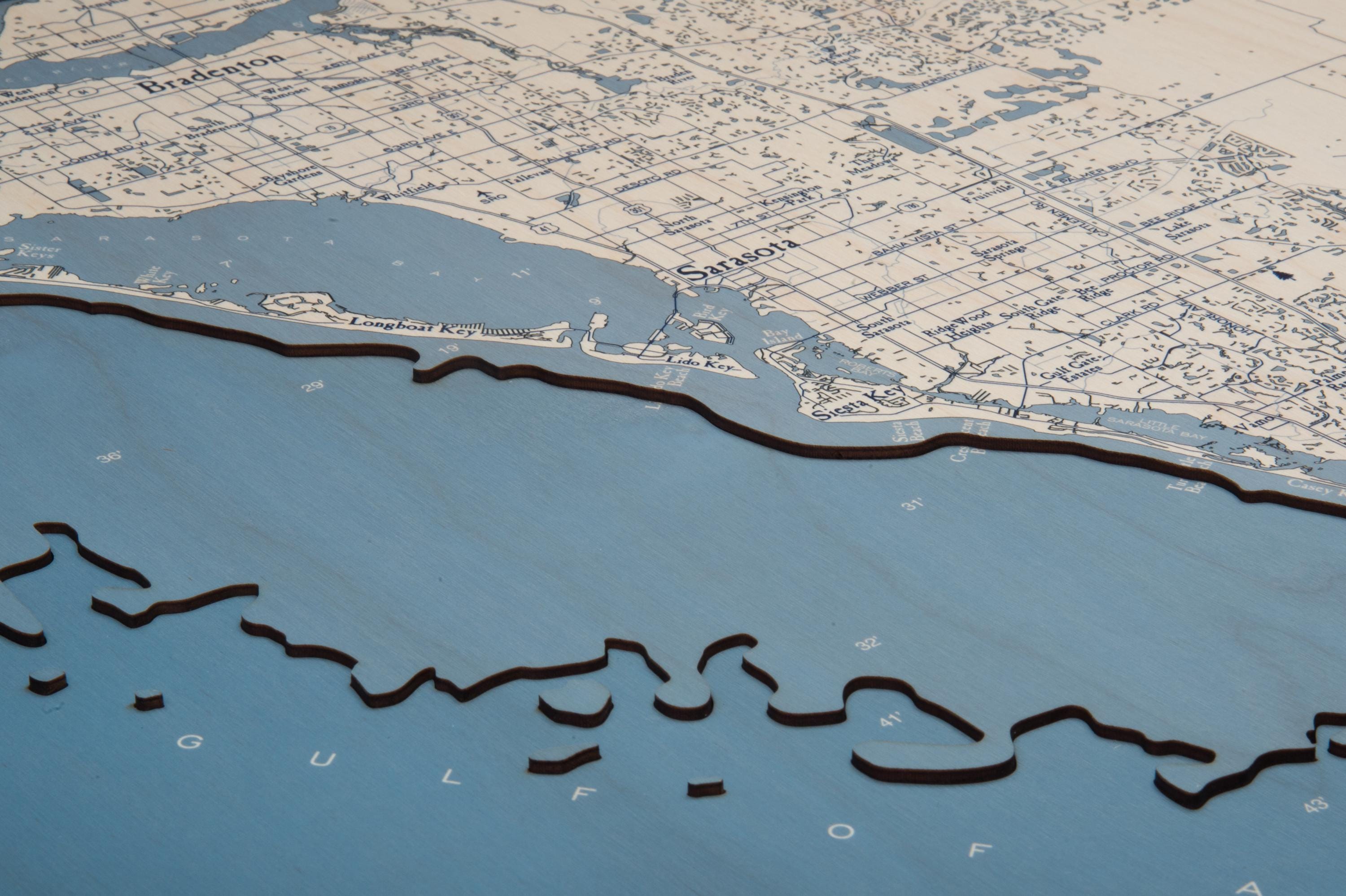 Sarasota to Venice, Florida 3D layered wood map in laser-cut Baltic birch, shown framed against a light wall