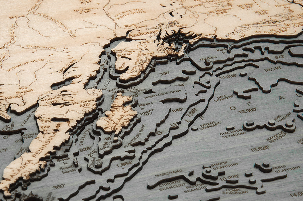 Alaska 3D layered wood map in laser-cut Baltic birch, shown framed against a light wall