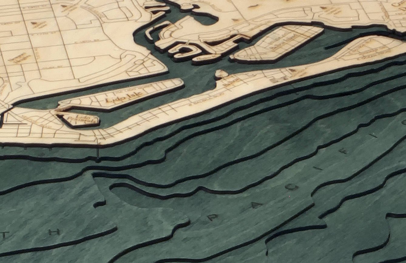 Newport Beach, California 3D layered wood map in laser-cut Baltic birch, shown framed against a light wall