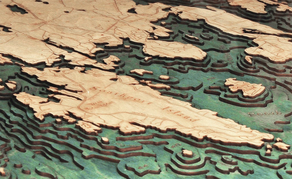 Boothbay Harbor, Maine 3D layered wood map in laser-cut Baltic birch, shown framed against a light wall