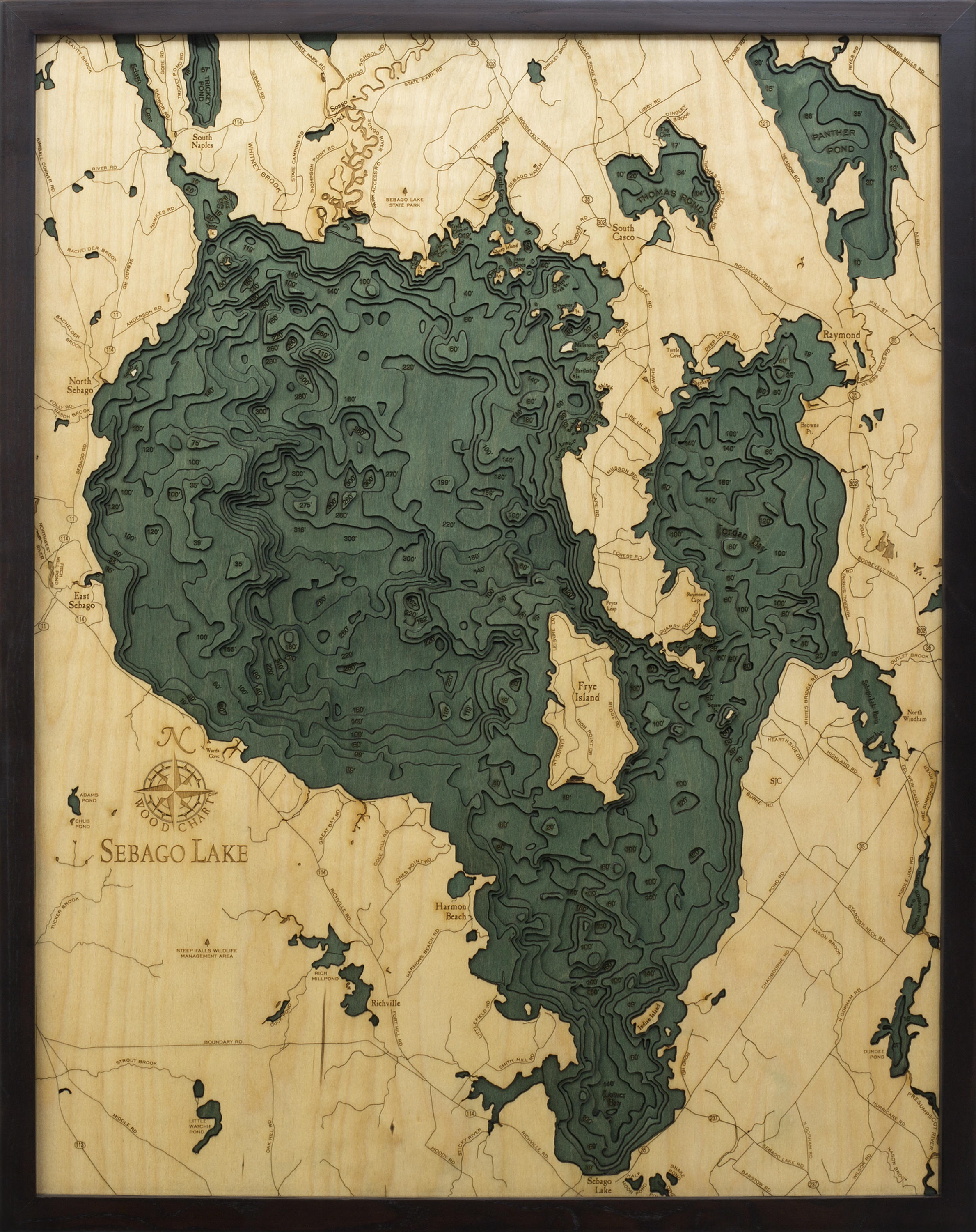 Sebago Lake, Maine 3D layered wood map in laser-cut Baltic birch, shown framed against a light wall