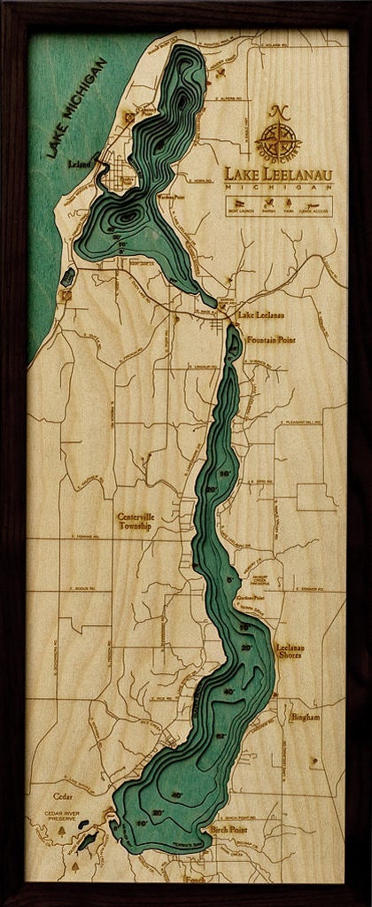 Lake Leelanau, Michigan 3D layered wood map in laser-cut Baltic birch, shown framed against a light wall