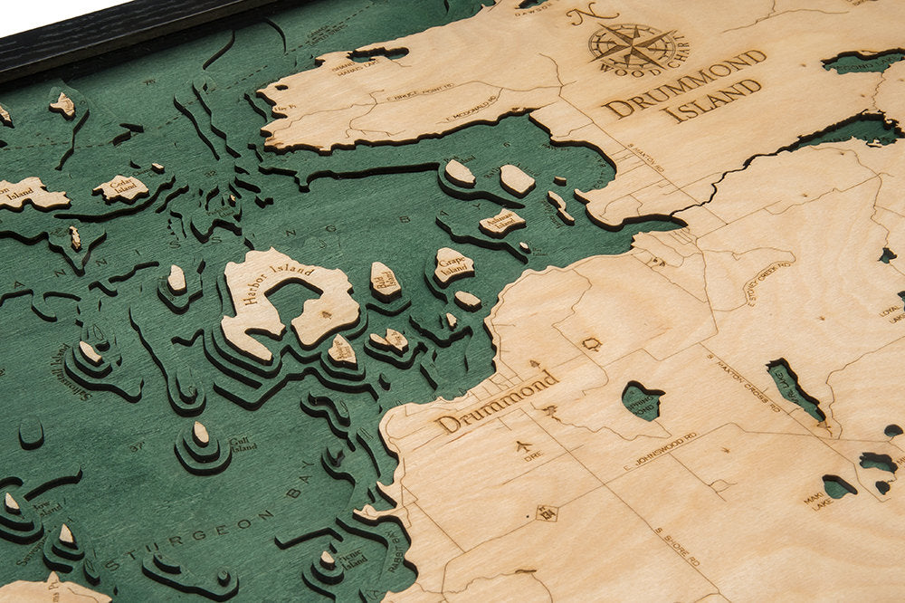 Drummond Island, Michigan 3D layered wood map in laser-cut Baltic birch, shown framed against a light wall