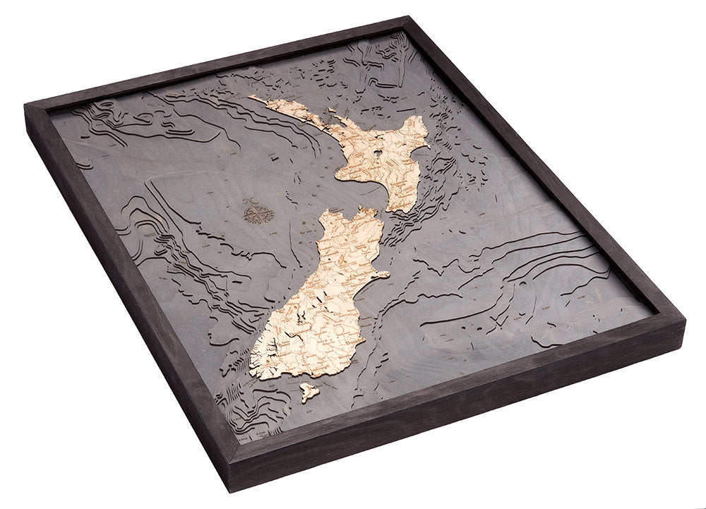New Zealand 3D layered wood map in laser-cut Baltic birch, shown framed against a light wall