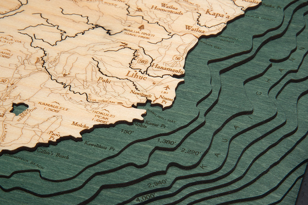 Kauai, Hawaii 3D layered wood map in laser-cut Baltic birch, shown framed against a light wall