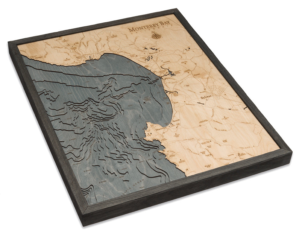 Monterey Bay, California 3D layered wood map in laser-cut Baltic birch, shown framed against a light wall