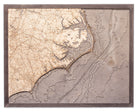 North Carolina Coast 3D layered wood map in laser-cut Baltic birch, shown framed against a light wall