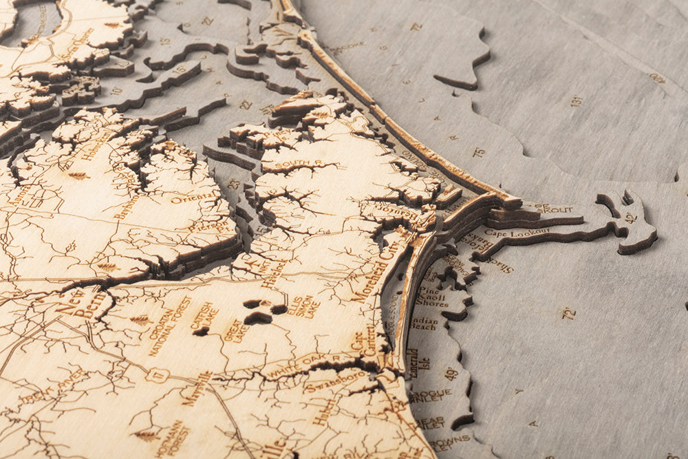 North Carolina Coast 3D layered wood map in laser-cut Baltic birch, shown framed against a light wall