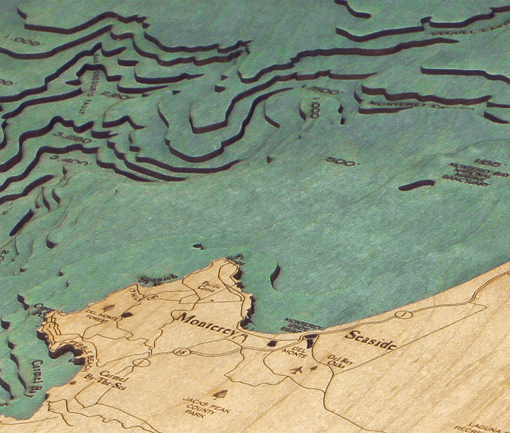 Monterey Bay, California 3D layered wood map in laser-cut Baltic birch, shown framed against a light wall