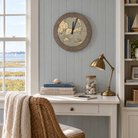 Cape Cod ring clock hanging on blue beadboard above a white writing desk next to a window over the marsh