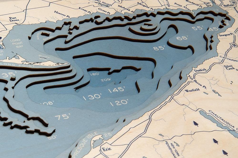 Lake Erie 3D layered wood map in laser-cut Baltic birch, shown framed against a light wall