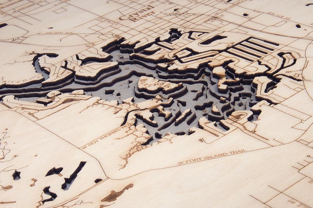 Crystal River, Florida 3D layered wood map in laser-cut Baltic birch, shown framed against a light wall