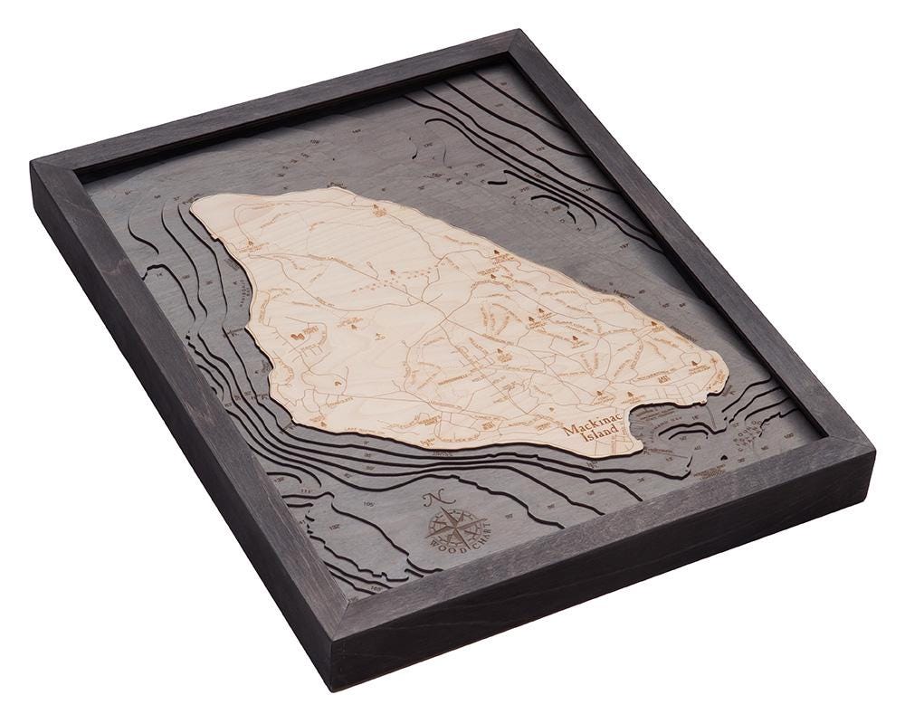 Mackinac Island, Michigan 3D layered wood map in laser-cut Baltic birch, shown framed against a light wall