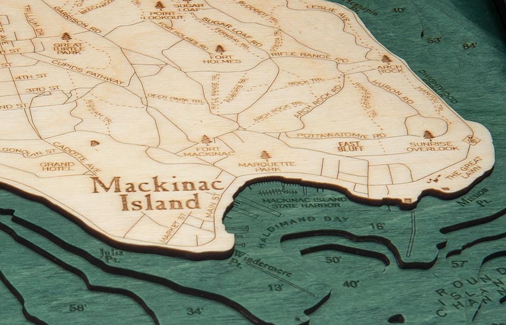Mackinac Island, Michigan 3D layered wood map in laser-cut Baltic birch, shown framed against a light wall