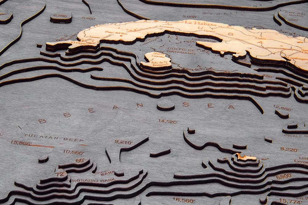 Gulf Of America 3D layered wood map in laser-cut Baltic birch, shown framed against a light wall