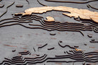 Gulf Of America 3D layered wood map in laser-cut Baltic birch, shown framed against a light wall