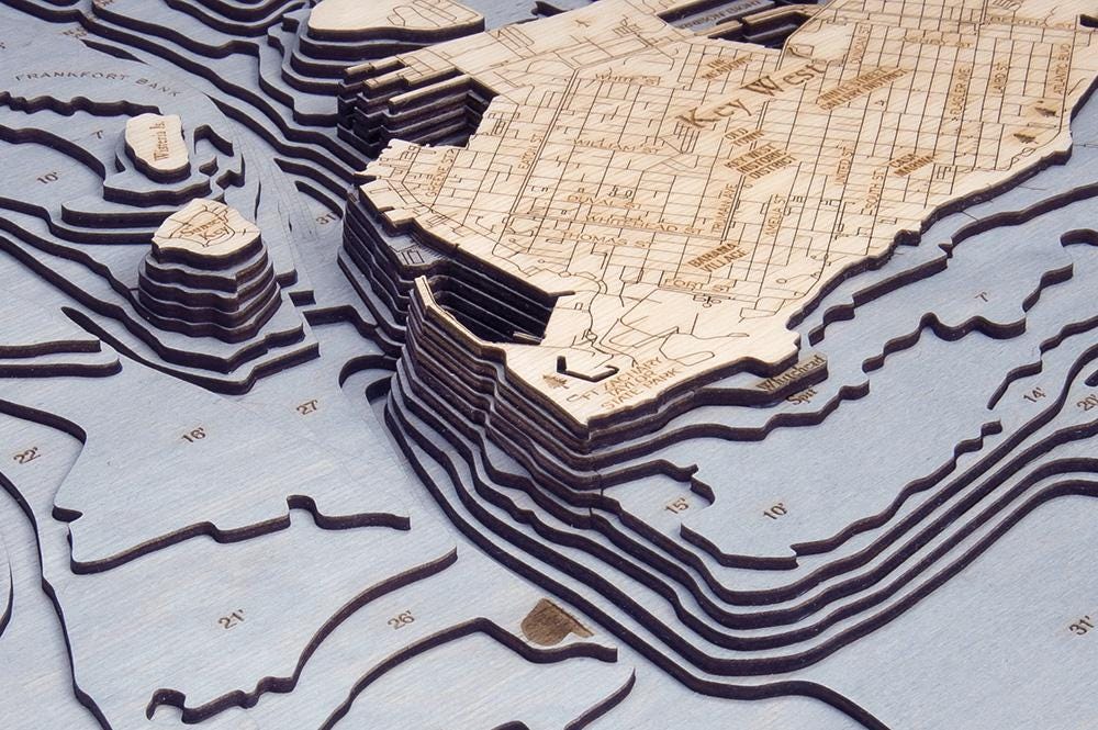 Key West, Florida 3D layered wood map in laser-cut Baltic birch, shown framed against a light wall