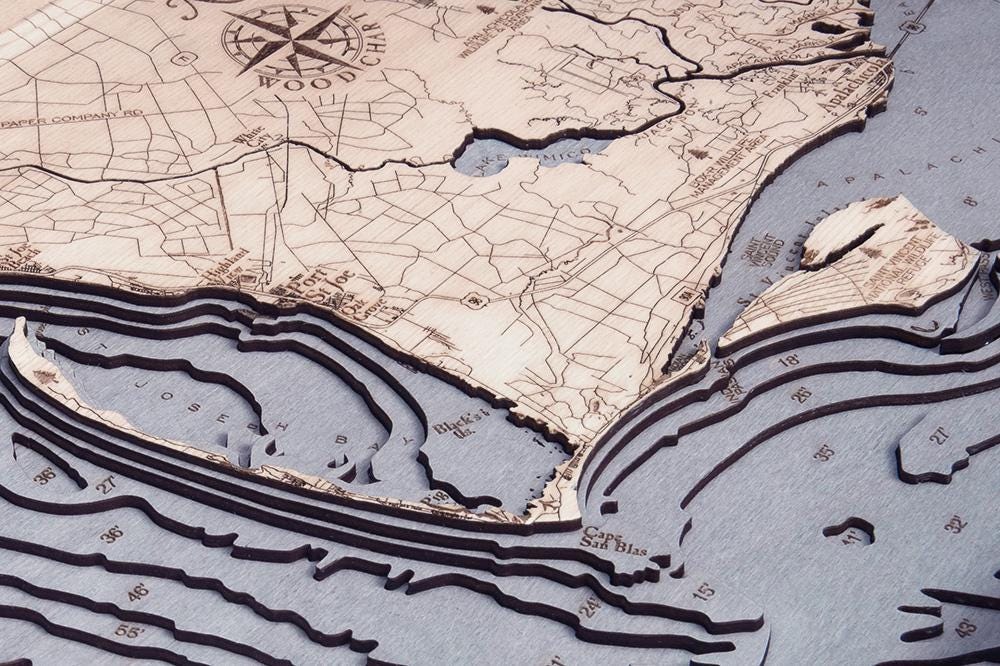 Mexico Beach to Bald Point, Florida 3D layered wood map in laser-cut Baltic birch, shown framed against a light wall