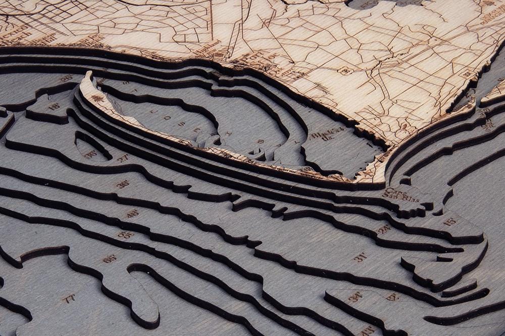 Mexico Beach to Bald Point, Florida 3D layered wood map in laser-cut Baltic birch, shown framed against a light wall