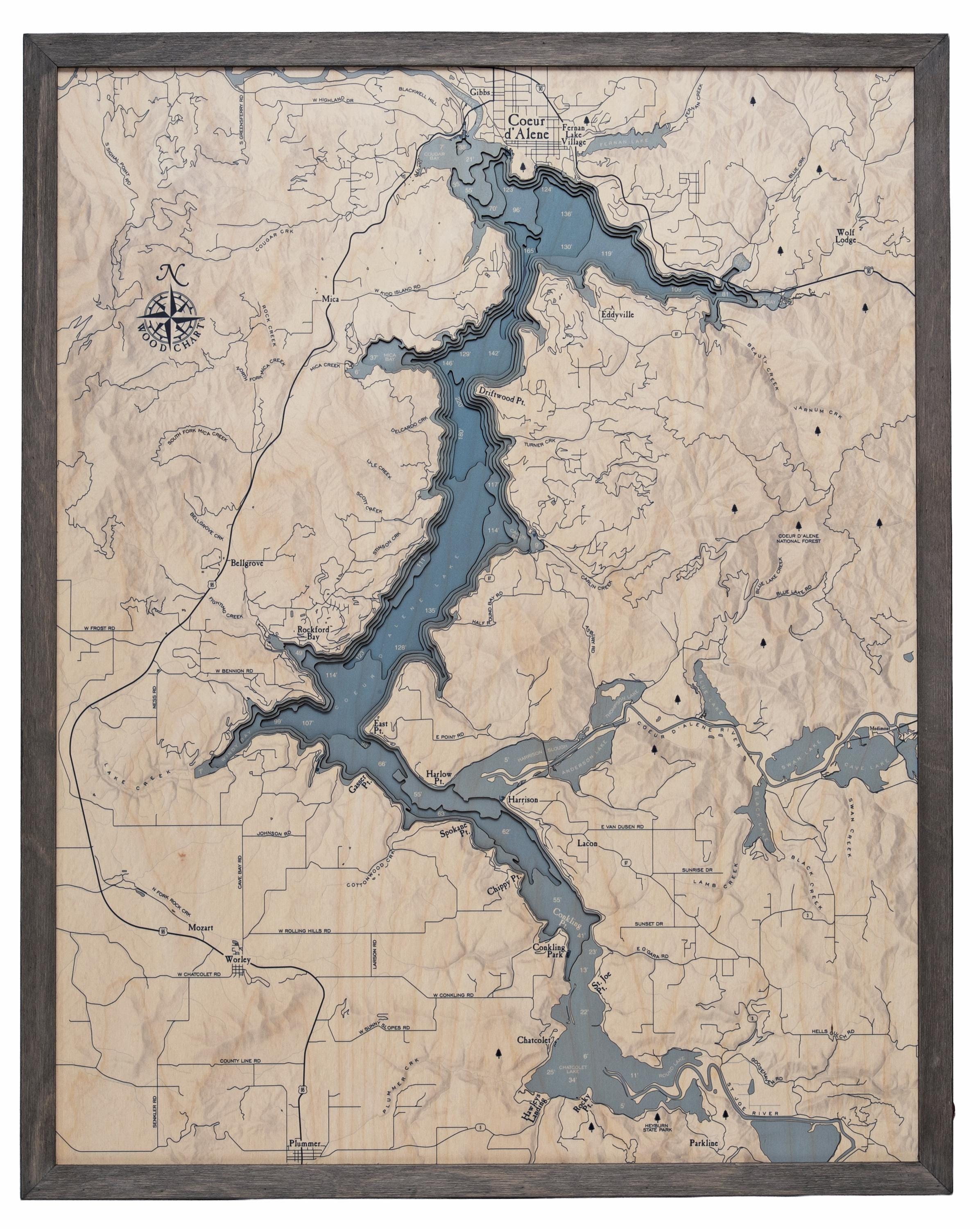 Lake Coeur d'Alene, Idaho 3D layered wood map in laser-cut Baltic birch, shown framed against a light wall