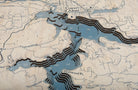 Lake Coeur d'Alene, Idaho 3D layered wood map in laser-cut Baltic birch, shown framed against a light wall