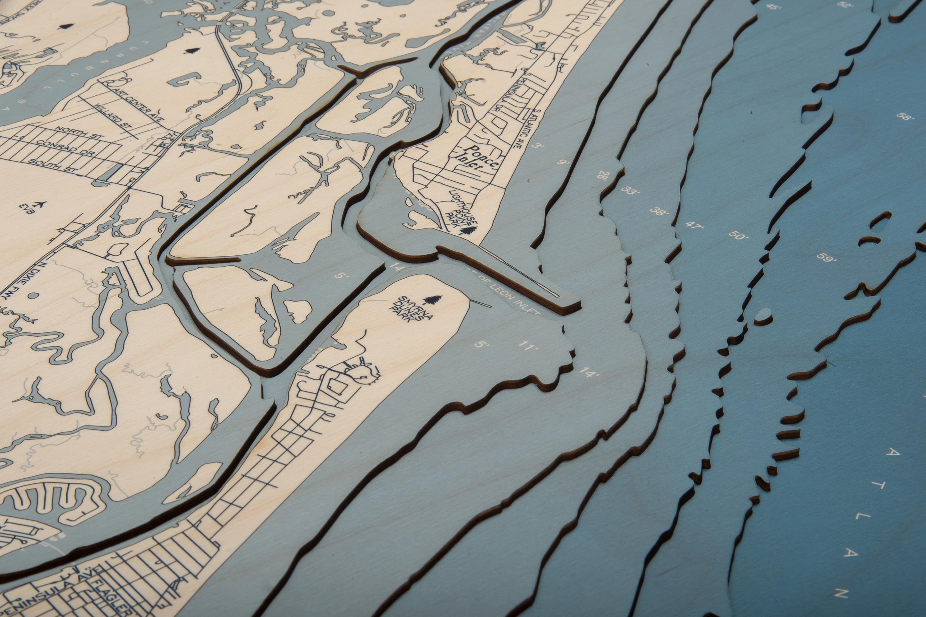 New Smyrna Beach, Florida 3D layered wood map in laser-cut Baltic birch, shown framed against a light wall