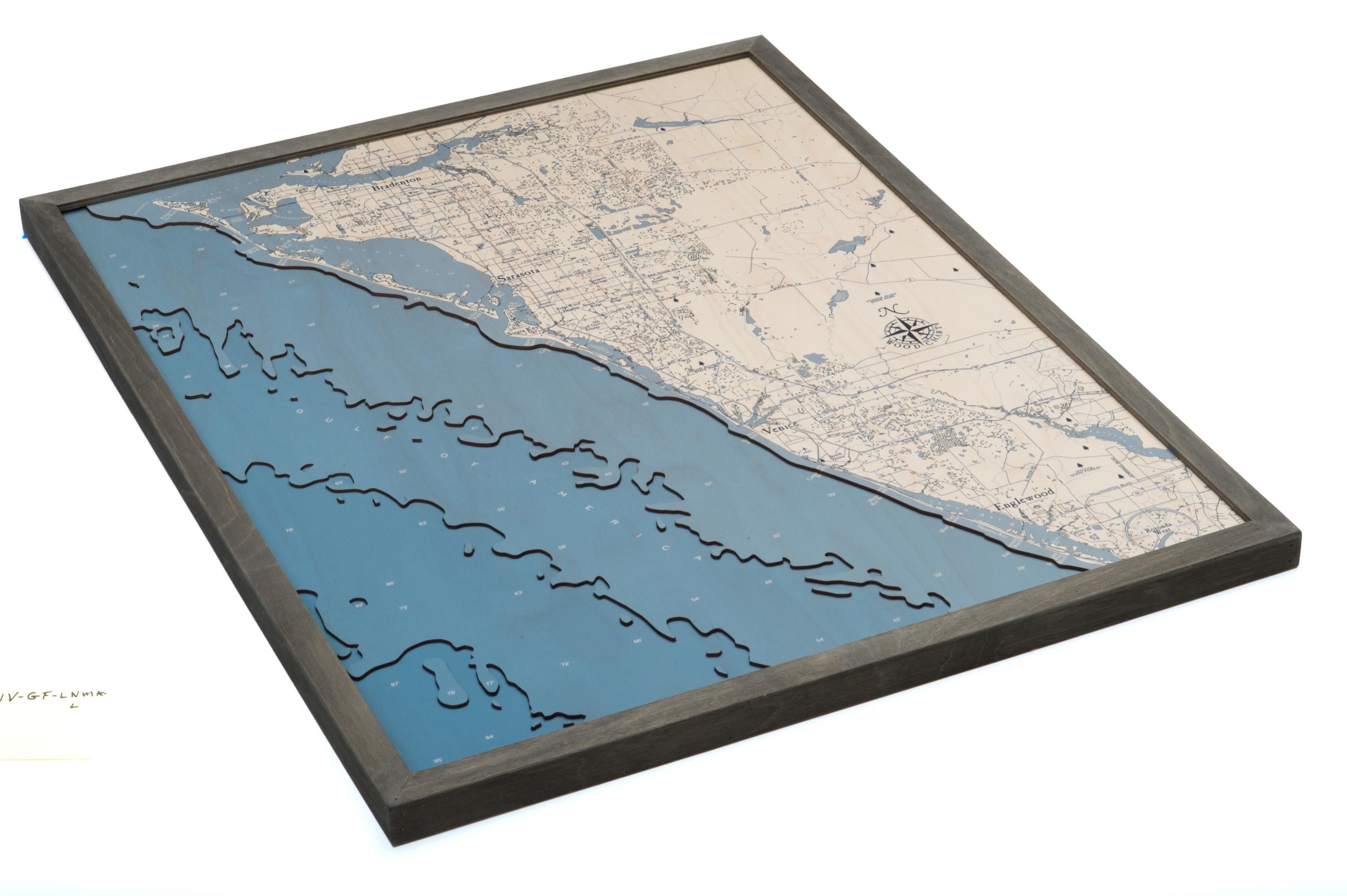 Sarasota to Venice, Florida 3D layered wood map in laser-cut Baltic birch, shown framed against a light wall