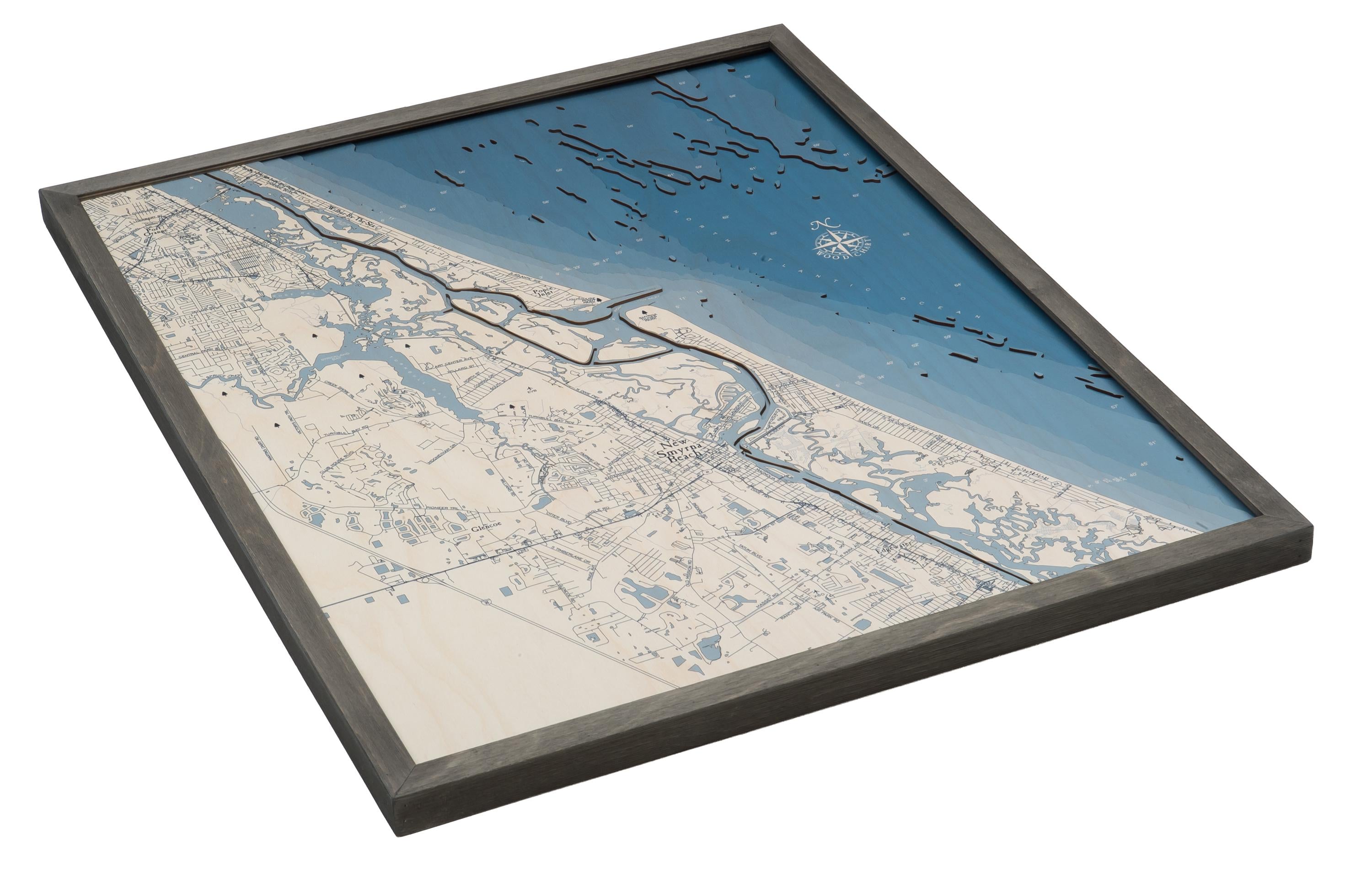 New Smyrna Beach, Florida 3D layered wood map in laser-cut Baltic birch, shown framed against a light wall