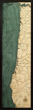 Oregon Coast 3D layered wood map in laser-cut Baltic birch, shown framed against a light wall