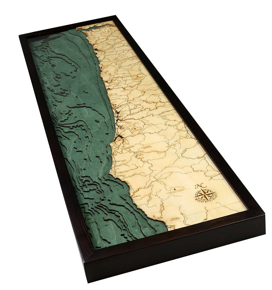 Oregon Coast 3D layered wood map in laser-cut Baltic birch, shown framed against a light wall