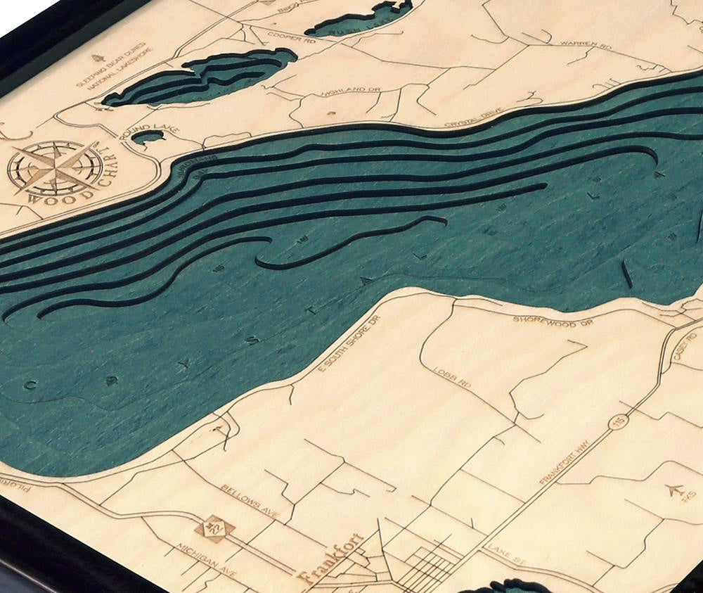 Crystal Lake, Michigan 3D layered wood map in laser-cut Baltic birch, shown framed against a light wall