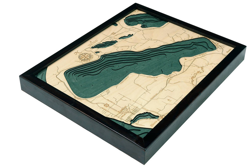 Crystal Lake, Michigan 3D layered wood map in laser-cut Baltic birch, shown framed against a light wall