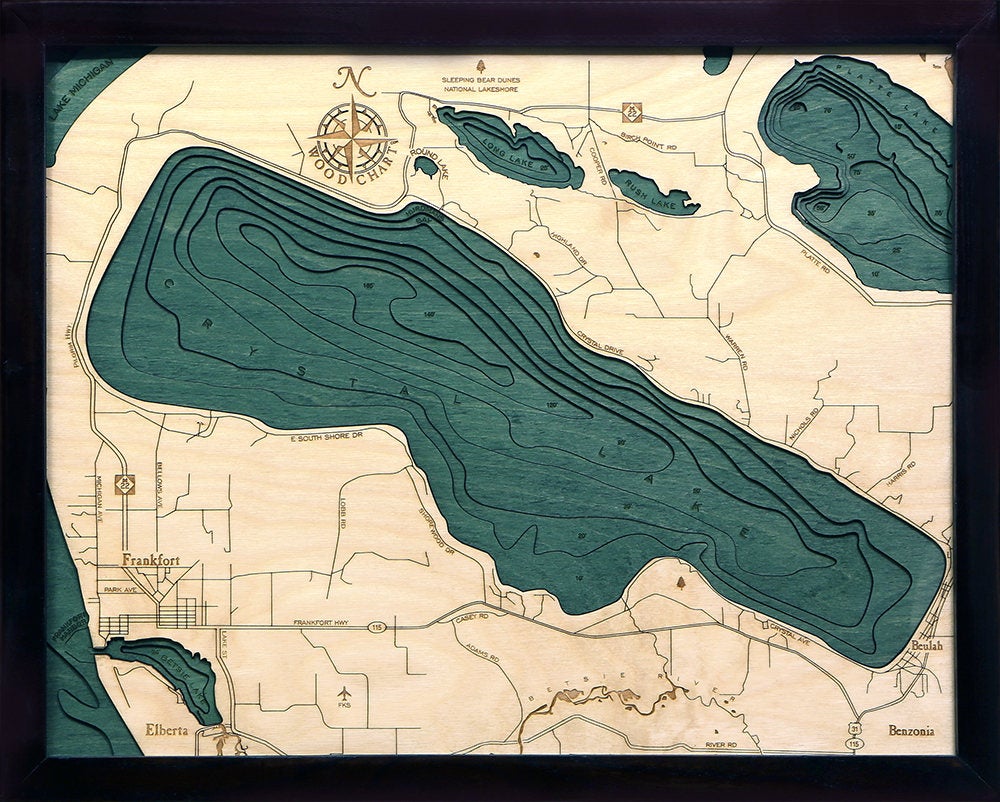 Crystal Lake, Michigan 3D layered wood map in laser-cut Baltic birch, shown framed against a light wall