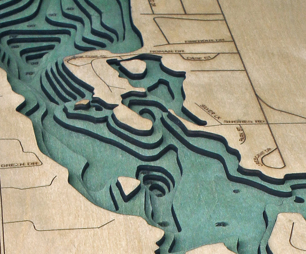 Silver Lake, Michigan 3D layered wood map in laser-cut Baltic birch, shown framed against a light wall