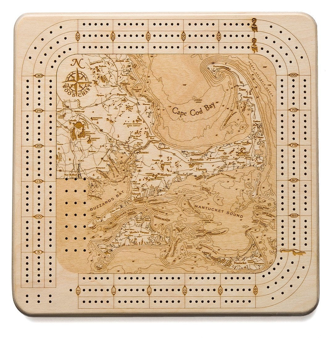 Cape Cod, Massachusetts wood cribbage board in laser-cut Baltic birch, shown framed against a light wall