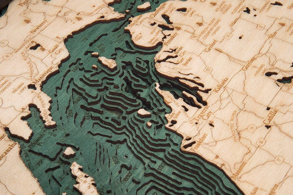 Lake Michigan 3D layered wood map in laser-cut Baltic birch, shown framed against a light wall