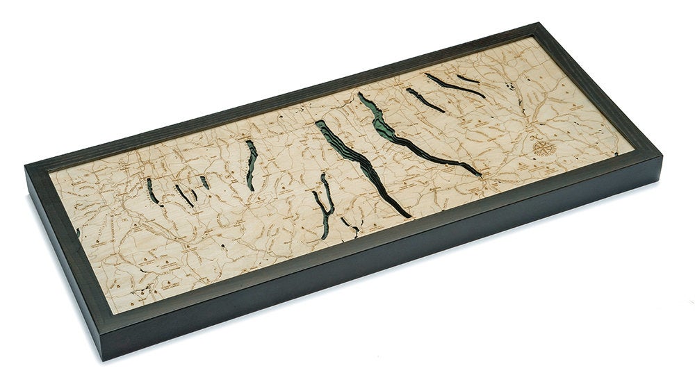 Finger Lakes, New York 3D layered wood map in laser-cut Baltic birch, shown framed against a light wall
