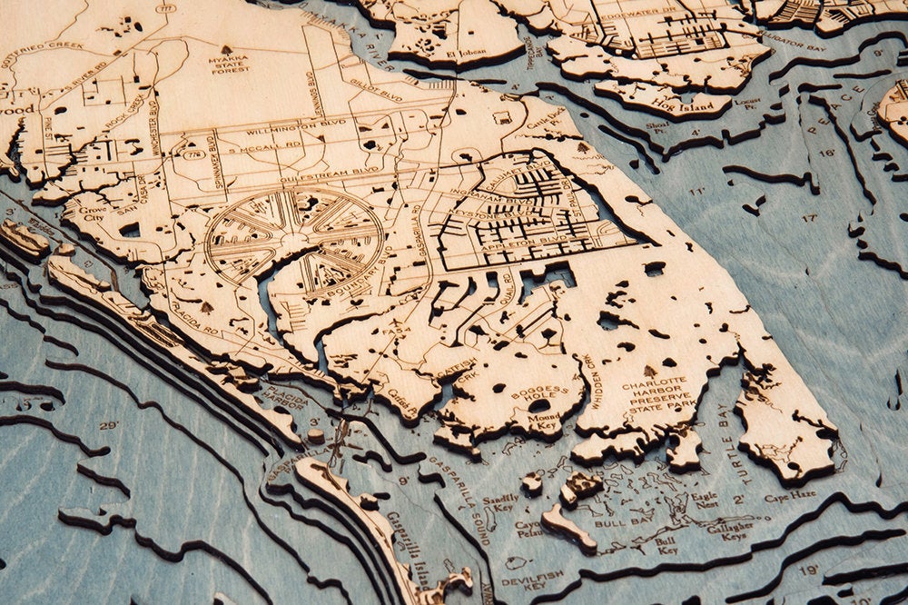 Charlotte Harbor, Florida 3D layered wood map in laser-cut Baltic birch, shown framed against a light wall