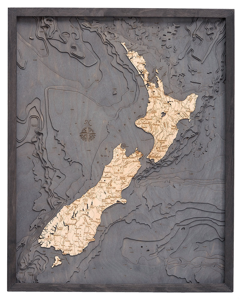 New Zealand 3D layered wood map in laser-cut Baltic birch, shown framed against a light wall