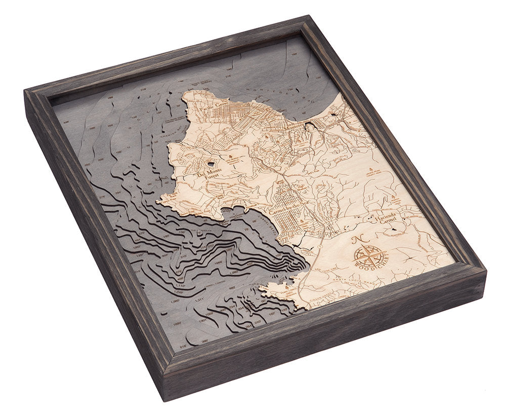 Carmel & Monterey, California 3D layered wood map in laser-cut Baltic birch, shown framed against a light wall