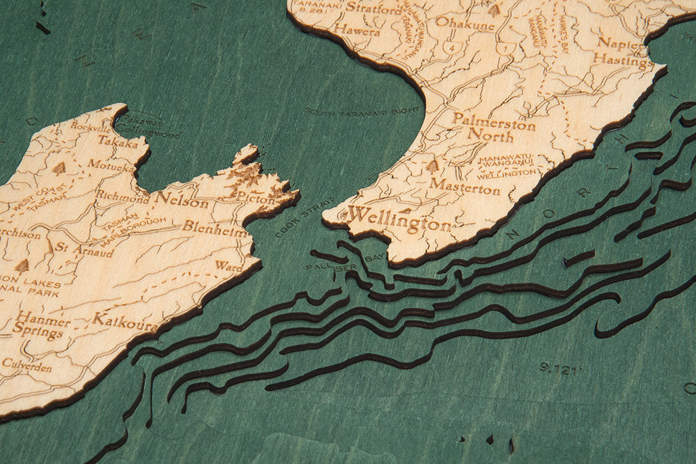 New Zealand 3D layered wood map in laser-cut Baltic birch, shown framed against a light wall