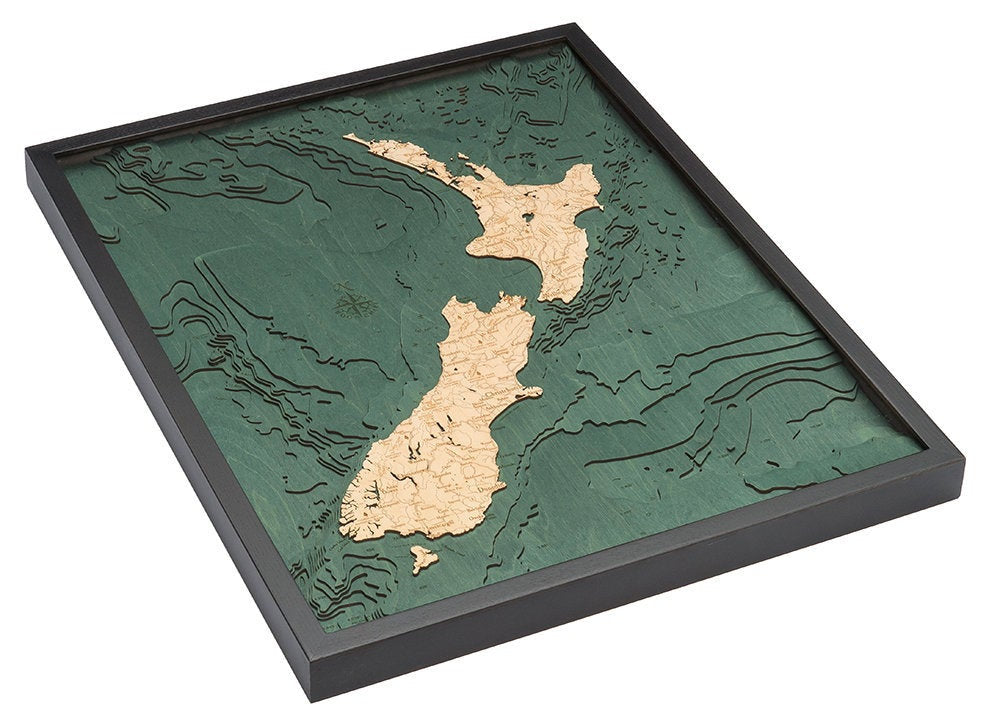 New Zealand 3D layered wood map in laser-cut Baltic birch, shown framed against a light wall
