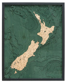 New Zealand 3D layered wood map in laser-cut Baltic birch, shown framed against a light wall
