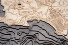 Carmel & Monterey, California 3D layered wood map in laser-cut Baltic birch, shown framed against a light wall
