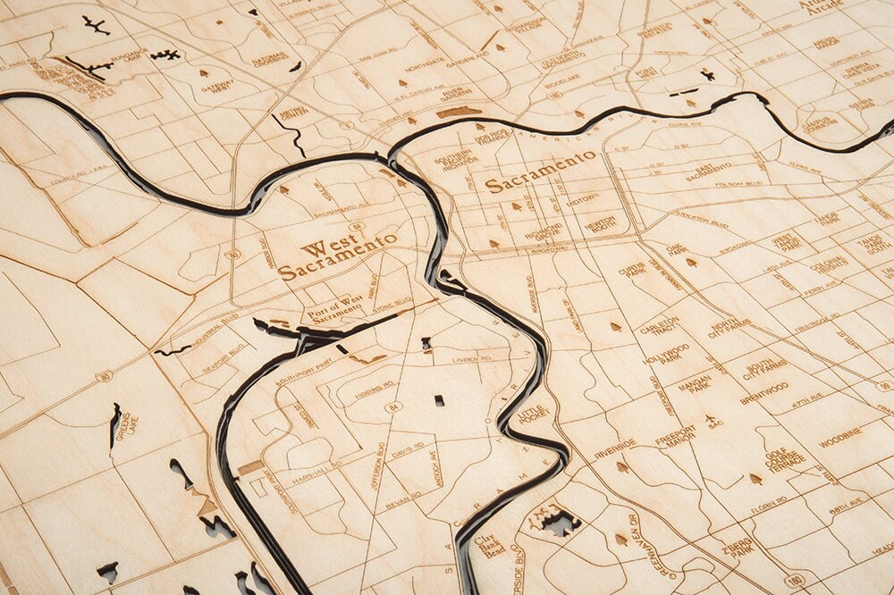 Sacramento, California 3D layered wood map in laser-cut Baltic birch, shown framed against a light wall