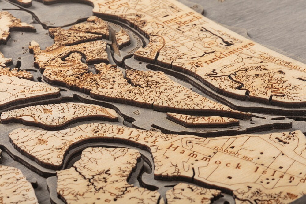 Amelia Island, Florida 3D layered wood map in laser-cut Baltic birch, shown framed against a light wall